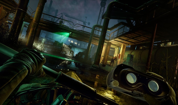 Bildet viser en spenningsfylt scene fra et videospill der spilleren manøvrerer en kajakk gjennom et mørkt industriområde. Personen i båten har på seg hansker og holder en åre. I forgrunnen til høyre ser vi nattsynsbriller, som gir inntrykk av at spilleren opererer i et stealth-scenario. Området er opplyst av grønne nattlys fra søkelys, som lyser opp de metalliske strukturene rundt. Det er synlige vakter på plattformene, mens store rør og kraner er en del av bakteppet. Dette skaper en dramatisk og mystisk atmosfære.